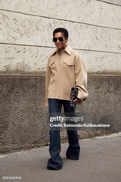 Tamu McPherson wears a beige oversized jacket with flared jeans and aviator sunglasses outside Sportmax show during the Milan Fashion Week Menswear...
