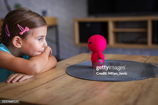 bambino che comunica con il robot giocattolo dell'intelligenza artificiale nel soggiorno - giocattoli foto e immagini stock