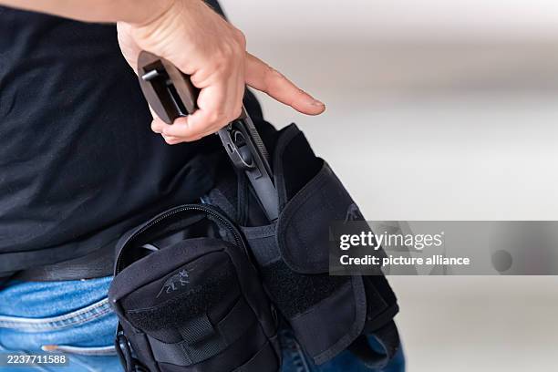 September 2025, Baden-Württemberg, ---: A marksman draws a .22 lfB caliber handgun from his holster during training at a shooting range. Handguns in...