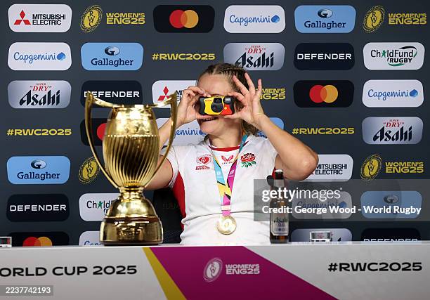 Zoe Aldcroft of England takes a photo on a Kodak camera as she speaks to the media in a post match press conference with the trophy following victory...