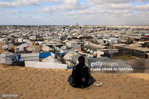 Palestinian woman sits overlooking a camp for displaced people in Khan Yunis in the southern Gaza Strip, on September 29 as the conflict between...