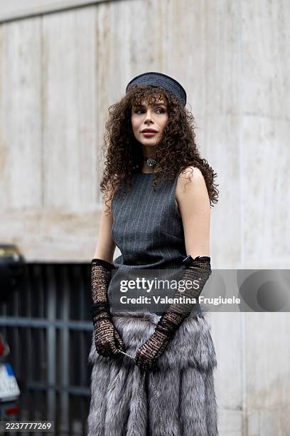 Guest wears a grey hat, a grey striped sleeveless top, black lace long gloves, a grey fur midi skirt, a black leather mini bag and a black necklace...