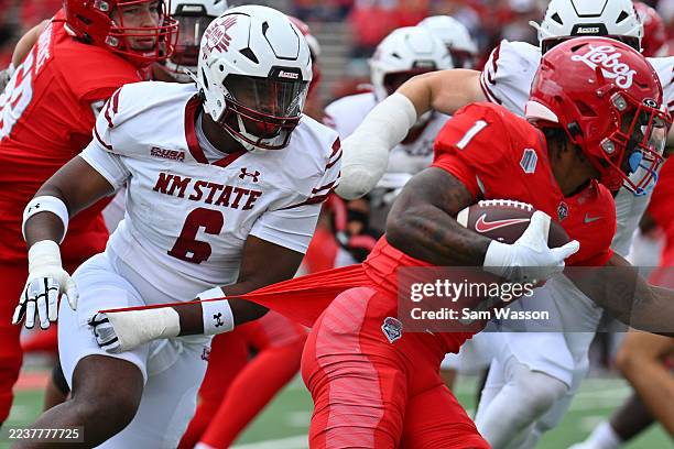 Defensive End Jamall Thompson Jr. #6 of the New Mexico State Aggies grabs the shirt of running back Damon Bankston of the New Mexico Lobos as he...