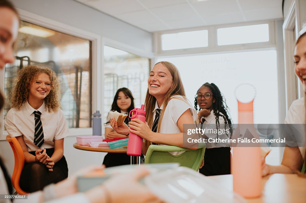 Group of Female Students laughing together in a cafeteria, during a School Break