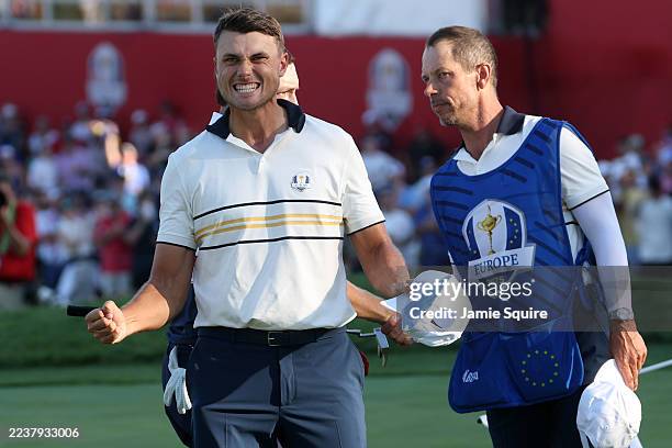 Ludvig Aberg of Team Europe and caddie Joe Skovron react after defeating Patrick Cantlay of Team United States on the 18th green during the Sunday...