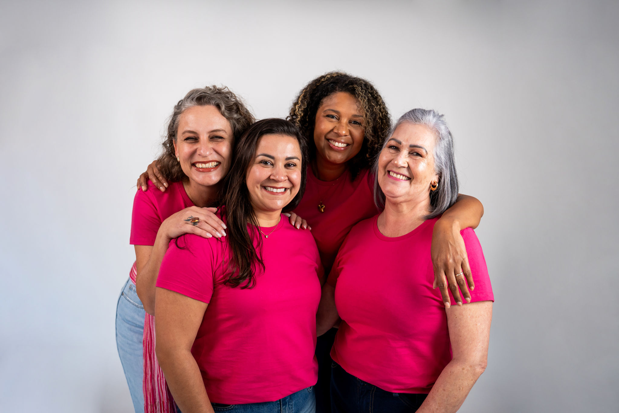 Group of women hugging each other wearing a pink t-shirt to raise awareness about breast cancer Group of women hugging each other wearing a pink t-shirt to raise awareness about breast cancer