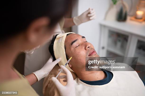 male client receiving cosmetic injection at modern aesthetic clinic - mesotherapy stock pictures, royalty-free photos & images