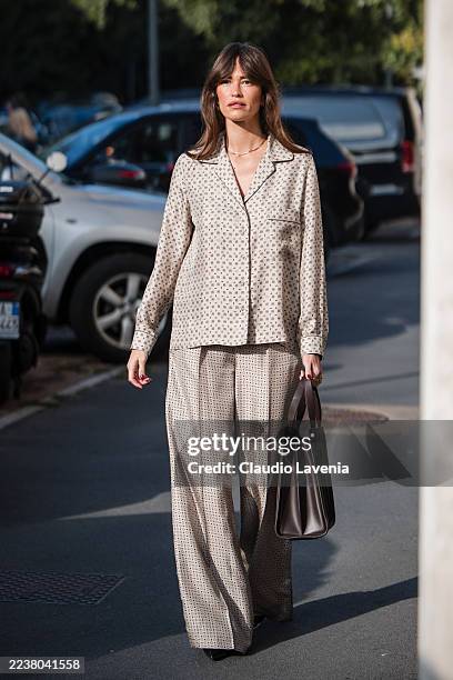 Alison Toby wears a silky patterned pajama set with a long-sleeve button-down shirt with contrasting piping and matching wide-leg trousers, black...