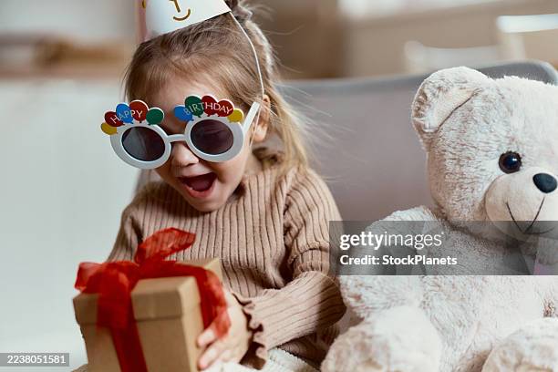 little girl opening birthday present with excitement. - birthday gift stock pictures, royalty-free photos & images