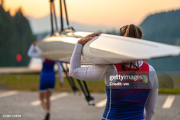 women rowing team carrying double scull boat near lake - sport rowing stock pictures, royalty-free photos & images