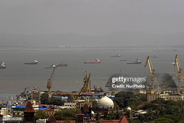 General view shows cargo ships and other vessels anchored in the Arabian Sea off the Mumbai coastline, with dockyard cranes visible in the...