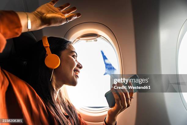 joyful passenger listening to music and dancing in airplane window seat - aeroplane part stock pictures, royalty-free photos & images