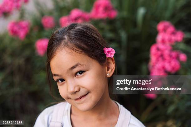 girl portrait with pink flower by ear, summer garden floral background - douceur photos et images de collection
