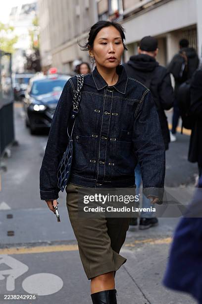 Guest wears blue denim jacket, khaki green bermuda pants, black boots, blue tote bag, outside Hodakova, during the Womenswear Spring Summer 2026 as...