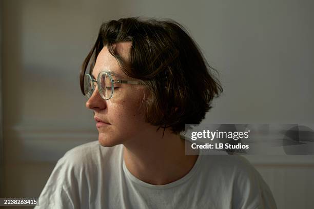 a woman in glasses with short hair looks to the side in a softly lit room. brussels, belgium - shy stock pictures, royalty-free photos & images