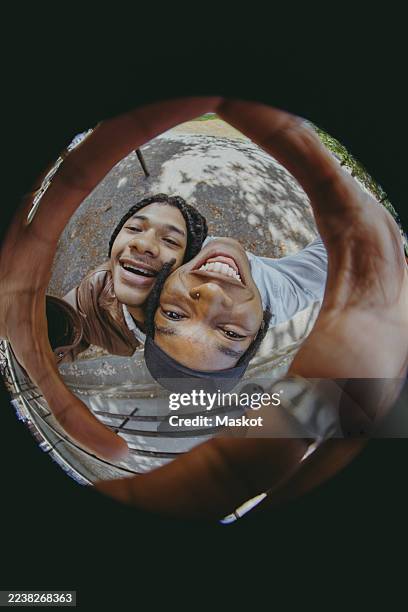 directly above portrait of smiling young male friends taking selfie while leaning on each other's shoulder in fish eye p - objetiva olho de peixe imagens e fotografias de stock