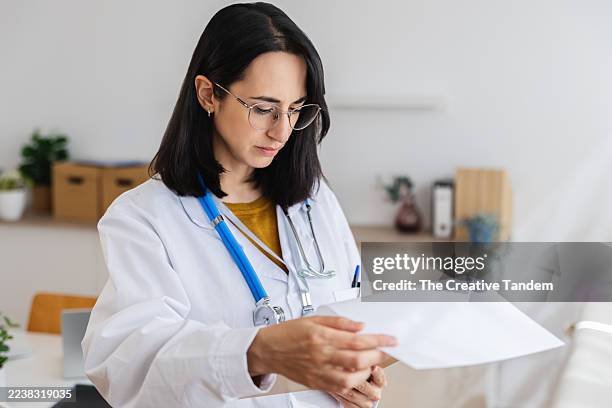 female doctor consulting medical records in clinic - medical test results stock pictures, royalty-free photos & images