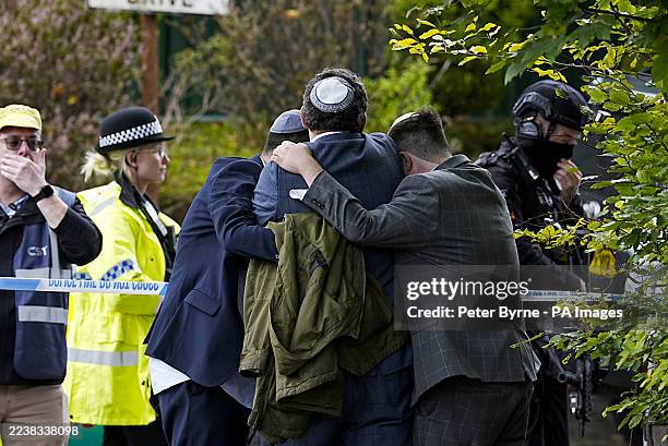 Members of the Jewish community comfort each other near to the Heaton Park Hebrew Congregation synagogue in Crumpsall, Manchester, where two people...