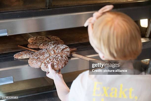October 2025, Baden-Württemberg, Stuttgart: Sophie Henne, owner of the sourdough bakery Brotique, takes sourdough bread out of an oven. Photo:...