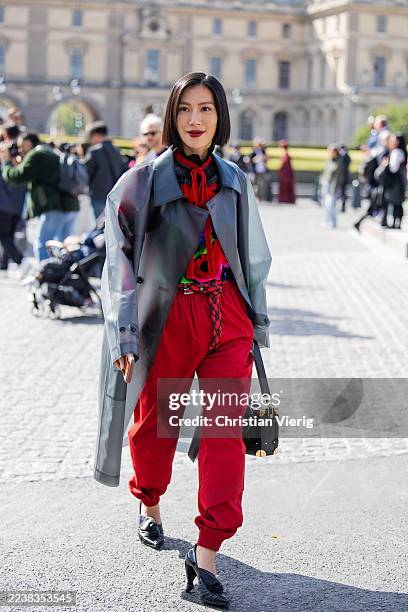 Molly Chiang wears grey transparent coat, red pants, red black turtleneck, black bag outside Louis Vuitton during the Womenswear Spring Summer 2026...