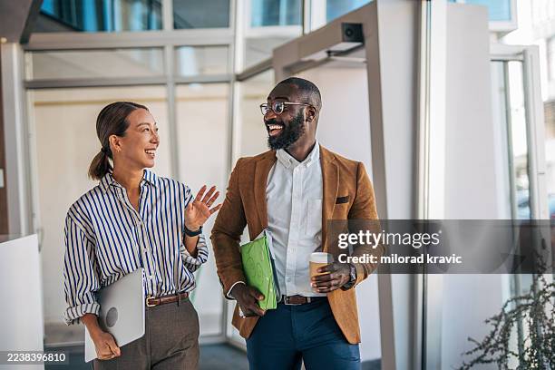 business colleagues walking and talking in modern office - coworker stock pictures, royalty-free photos & images