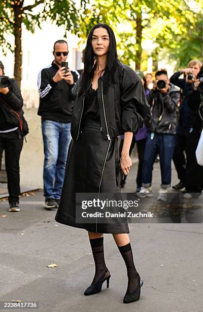 Model Maria Carla Boscono is seen wearing a black H&M bomber jacket, laced black top, black H&M skirt, black heels and black sheer knee high socks...