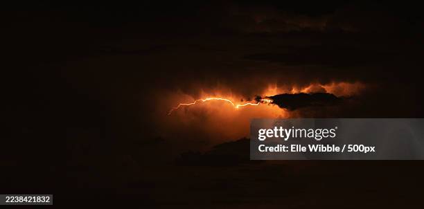 dramatic lightning strike illuminates dark stormy clouds at night - cloudy night sky stock pictures, royalty-free photos & images