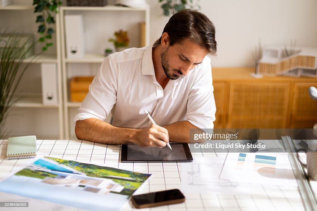 Architect sketching new project on digital tablet at office desk