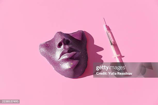 purple colored syringe and face/ mask on the pink background. - industrie de la mode photos et images de collection