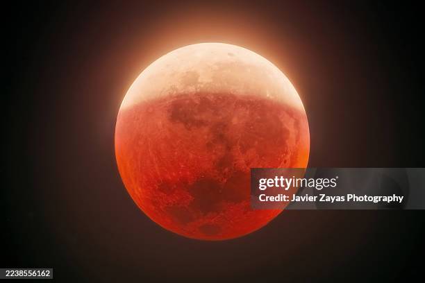 partial lunar eclipse casting red glow on moon - eclipse imagens e fotografias de stock