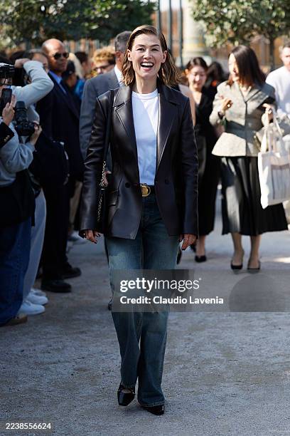 Rosamund Pike wears white t-shirt, dark brown leather blazer, medium wash jeans with Dior belt, black bag, , outside Dior, during the Womenswear...