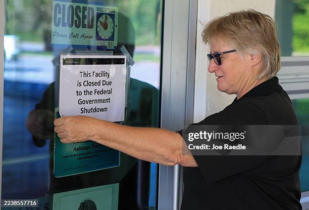 Caren Kopania removes a sign that reads, ' This Facility is Closed Due to the Federal Government Shutdown', on the door to a gift shop in the...