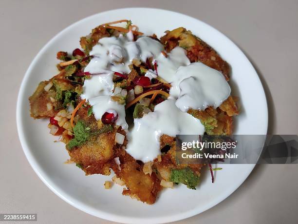aloo tikki chaat/potato cutlet/yogurt/in a white ceramic plate/white background - aloo tikki stock-fotos und bilder