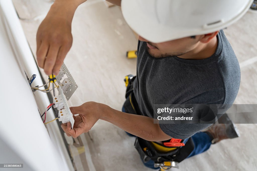 Electrician installing a power socket while working at a construction site