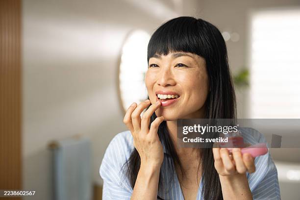 asiatische frau mit morgenroutine im badezimmer - lippenpflege stock-fotos und bilder