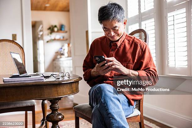 senior man using smartphone in his home - generation x stock pictures, royalty-free photos & images