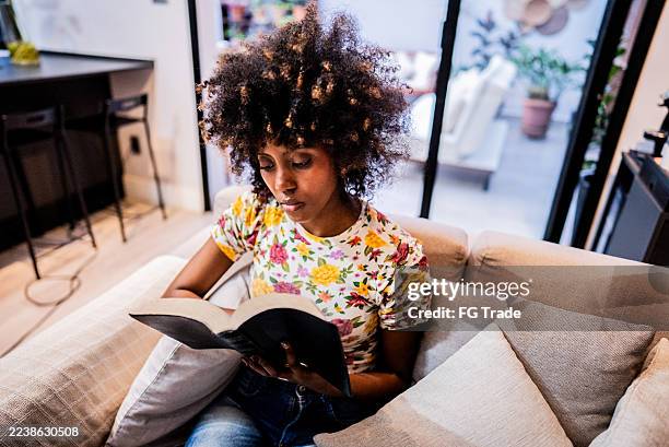 young woman reading bible at home - theology stock pictures, royalty-free photos & images