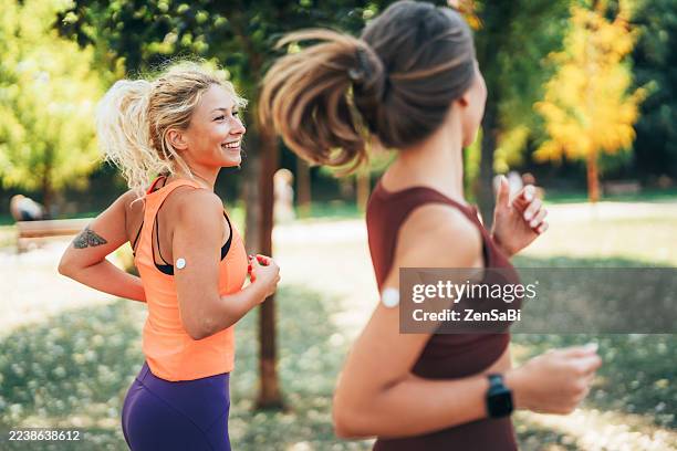 beautiful diabetic women running in the park with continuous glucose monitor - continuous glucose monitor stock pictures, royalty-free photos & images