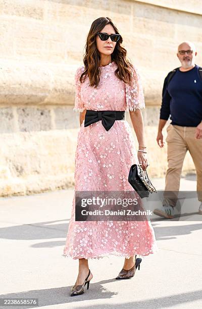 Guest is seen wearing a pink and white floral dress, black bow belt, Dior bag and black sunglasses outside the Dior show during the Womenswear Spring...