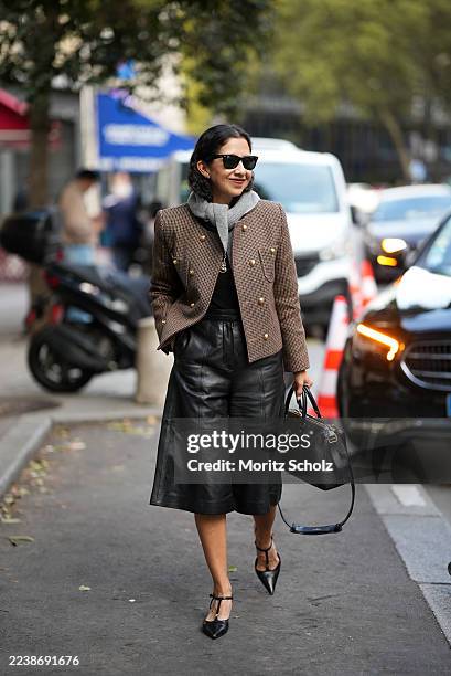 A guest is seen wearing a tailored double-breasted blazer in a brown houndstooth check pattern with gold buttons, structured shoulders and cropped...