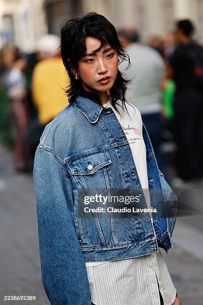 Nara Kim wears white striped shirt, white graphic pattern Acne Studios t-shirt, blue denim jacket, outside Acne Studios during the Womenswear Spring...