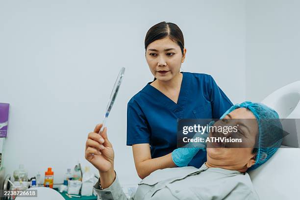 dermatologist examines woman’s face for anti-aging procedure consultation - hyperpigmentation stockfoto's en -beelden