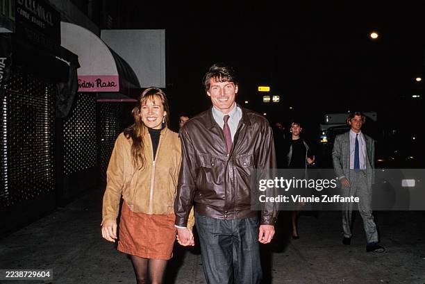 American actress and singer Dana Morosini, wearing a beige jacket and a burnt orange skirt, and her partner, American actor Christopher Reeve, who...