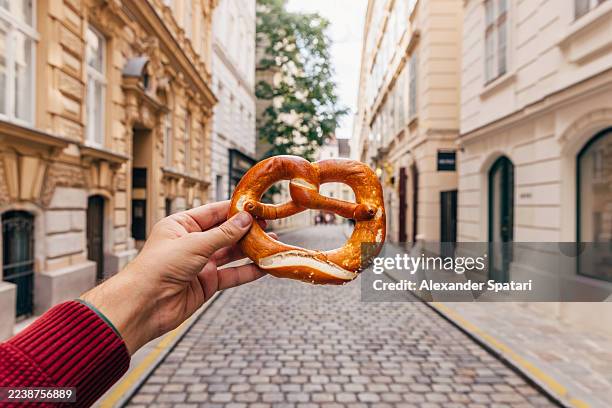 man holding pretzel on the street in vienna historic old town, personal perspective view, austria - gastronome photos et images de collection