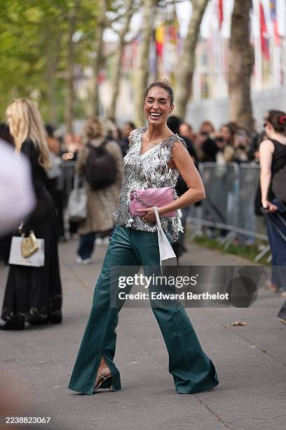 Guest wears hair pulled into a high bun, dark brown, gold hoop earrings, a pink quilted leather shoulder bag with a silver chain strap and a white...