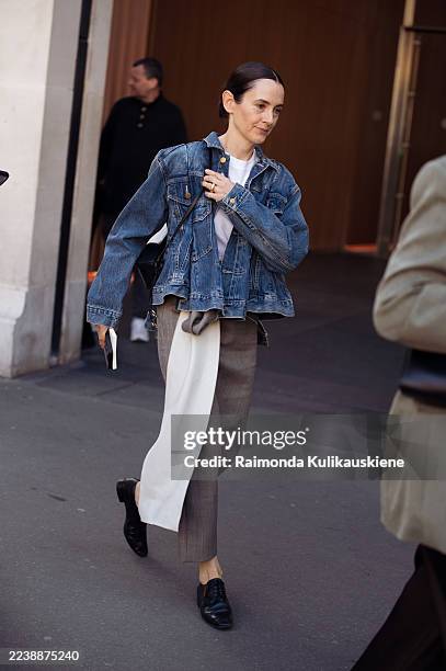 Guest wears a blue denim jacket over a white T-shirt, grey tailored trousers with a long cream scarf detail, and black leather lace-up shoes,...