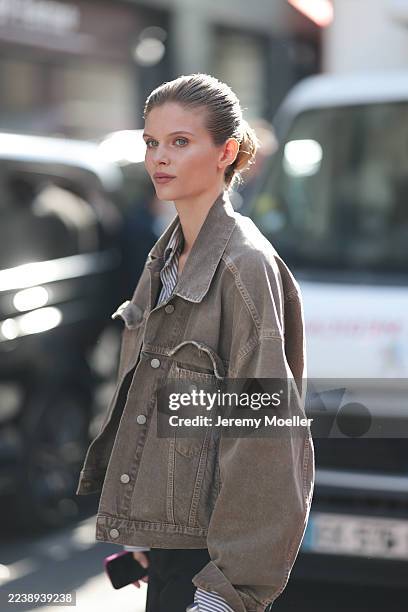 Blonde-haired woman seen wearing a grey brown jeans jacket, blue and white striped blouse, black pants and an Iphone outside The Row Show during the...