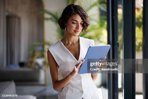 élégante jeune femme d’affaires utilisant une tablette numérique dans le hall d’un hôtel moderne - richesse photos et images de collection