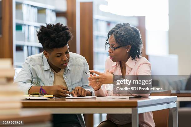 mentor guides a young student in a classroom setting, fostering learning and development. - study guide stock pictures, royalty-free photos & images