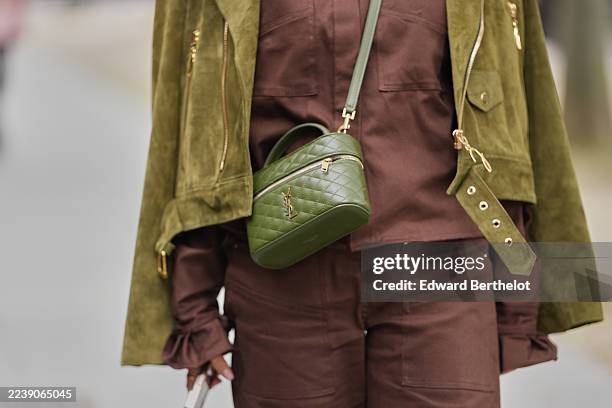 Guest wears a green quilted leather crossbody bag from Saint Laurent with top handle and gold hardware, an olive green suede biker jacket with gold...